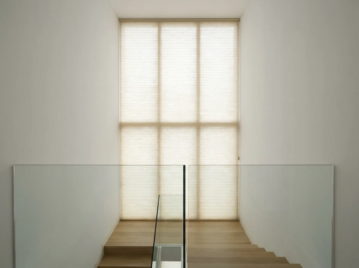 Cellular honeycomb blind on a tall stairwell window, double-cell fabric fully lowered