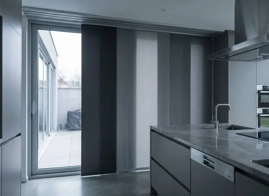 Panel blind with broad fabric panels sliding on a ceiling track across a glass wall